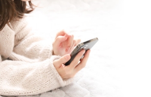 リラックスした姿勢でスマートフォンを操作する女性のイメージ写真
